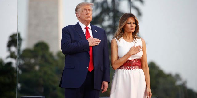 President Donald Trump and first lady Melania Trump place their hands on their chest during a 