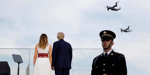 President Donald Trump and first lady Melania Trump watch as V-22 Osprey aircraft perform a flyover during a 