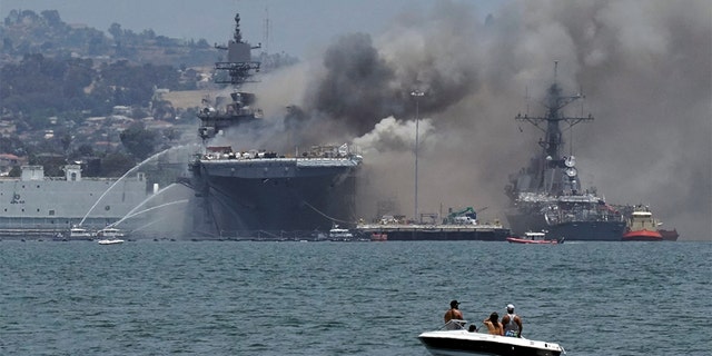 Firefighting boats spray water onto the U.S. Navy amphibious assault ship USS Bonhomme Richard as smoke rises from a fire onboard the ship at Naval Base San Diego, as seen from Coronado, California, U.S. July 12, 2020. REUTERS/Bing Guan - RC2WRH9BLDW4