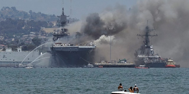 Firefighting boats spray water onto the U.S. Navy amphibious assault ship USS Bonhomme Richard as smoke rises from a fire onboard the ship at Naval Base San Diego, as seen from Coronado, California, U.S. July 12, 2020. REUTERS/Bing Guan - RC2WRH9BLDW4