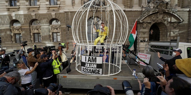 Fashion designer Vivienne Westwood sits suspended in a giant bird cage in protest against the extradition of WikiLeaks founder Julian Assange to the U.S., outside the Old Bailey court, in London, Tuesday, July 21, 2020. Assange is in London's Belmarsh Prison awaiting a full extradition hearing, which has been postponed because of the coronavirus pandemic. Originally due to begin in May, it is now scheduled to start on Sept. 7 at the Old Bailey. (AP Photo/Matt Dunham)