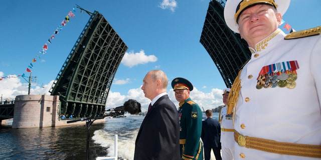 President Vladimir Putin, left, Admiral Nikolai Yevmenov, Commander-in-Chief of the Russian Navy, right, and Russian Defence Minister Sergei Shoigu inspect warships during the Navy Day parade in St.Petersburg, Russia, on Sunday, July 26, 2020. (Alexei Druzhinin, Sputnik, Kremlin Pool Photo via AP)