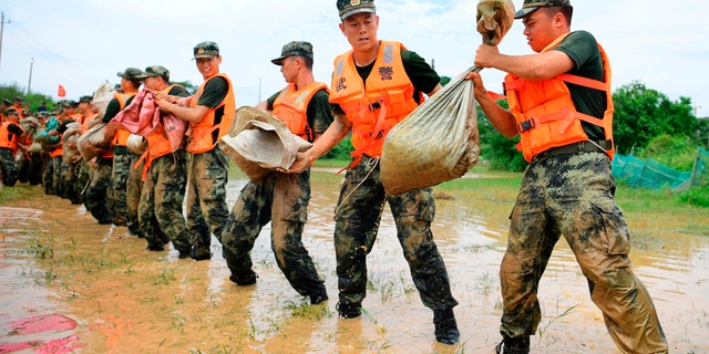 In this photo released by Xinhua News Agency, Chinese paramilitary policemen form a line to move sandbags to reinforce a dike along the banks of Poyang Lake in Poyang County in eastern China's Jiangxi Province, July 12.