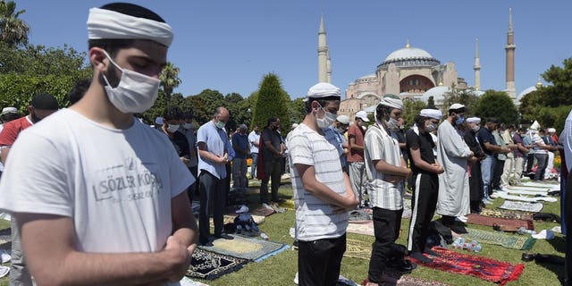 Muslims pray during Friday prayers at the historic Sultanahmet district of Istanbul, near the Byzantine-era Hagia Sophia, background, Friday, July 24, 2020.