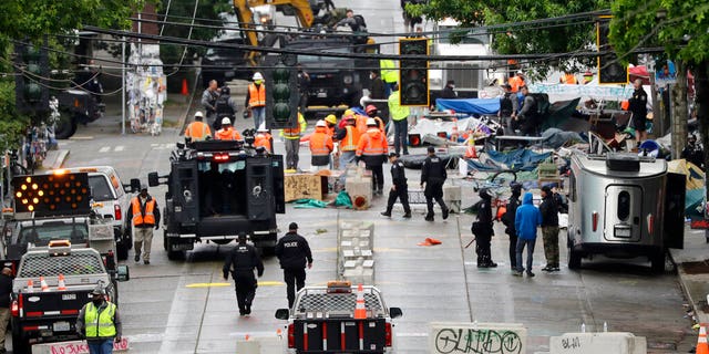 Police and city workers fill a street occupied hours earlier by an encampment of protesters Wednesday, July 1, 2020, in Seattle, where streets had been blocked off in an area demonstrators had occupied for weeks.