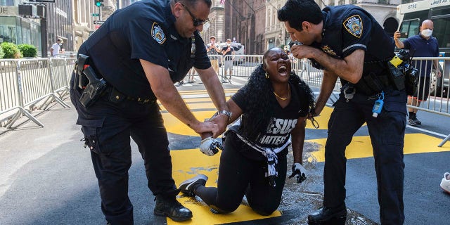 New York Police Department officers attempt to detain a protester who they say used black paint to deface the Black Lives Matter mural outside of Trump Tower on Fifth Avenue Saturday. (AP Photo/Yuki Iwamura)