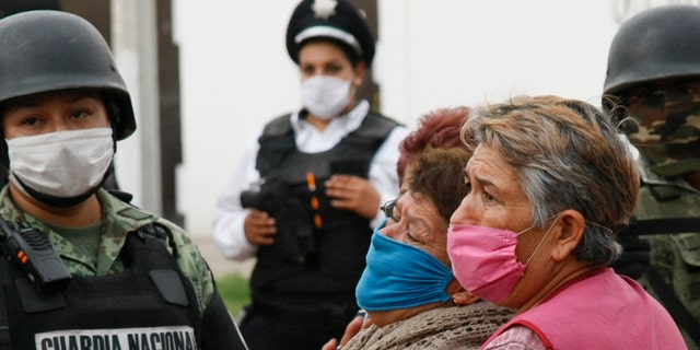 Relatives of the victims of a shooting at an unregistered drug rehabilitation center wait in anguish outside the rehab center in Irapuato, Mexico, Wednesday, July 1, 2020. (Associated Press)