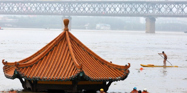 Residents swim past a riverside pavilion submerged by the flooded Yangtze River in Wuhan in central China's Hubei province July 8.