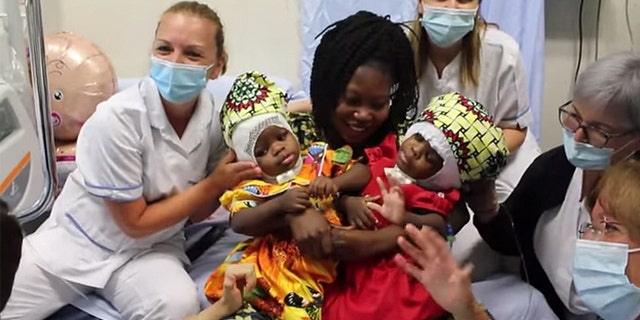 Ermine Nzotto holds her twins, Ervina and Prefina, after surgery. (Photo credit: Bambino Gesu Pediatric Hospital)