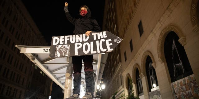 A protester holds a sign calling for the defunding of police at a protest on Saturday, July 25, 2020, in Oakland, Calif. (AP Photo/Christian Monterrosa)