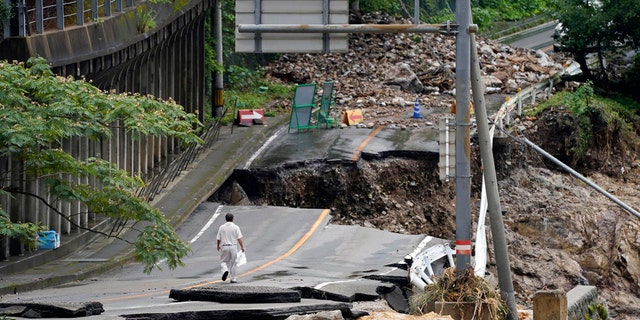 A man walks on a heavily damaged road following heavy rain in Kumamura, Kumamoto prefecture, southern Japan Monday, July 6, 2020.