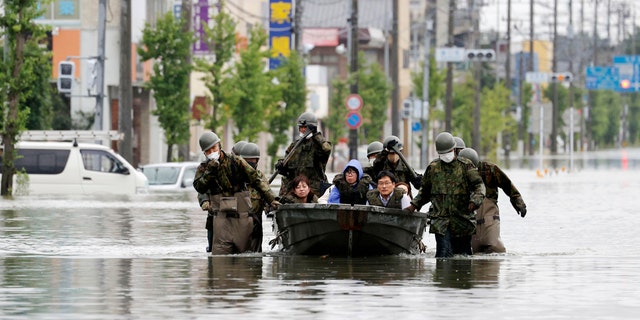 Japan Self Defense Force members rescue residents on a boat on a flooded road hit by heavy rain in Omuta, Fukuoka prefecture, southern Japan Tuesday, July 7, 2020.