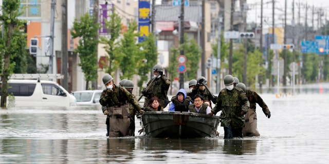 Japan Self Defense Force members rescue residents on a boat on a flooded road hit by heavy rain in Omuta, Fukuoka prefecture, southern Japan Tuesday, July 7, 2020.