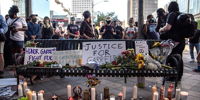 AUSTIN, TX - JULY 26: People gather around a makeshift memorial lined with flowers and candle at a vigil for Garrett Foster on July 26, 2020 in downtown Austin, Texas. Garrett Foster, 28, who was armed and participating in a Black Lives Matter protest, was shot and killed after a chaotic altercation with a motorist who allegedly drove into the crowd. The suspect, who has yet to be identified, was taken into custody. (Photo by Sergio Flores/Getty Images)