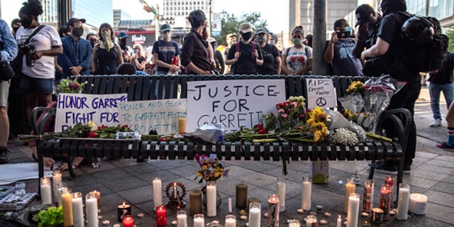 People gather around a makeshift memorial lined with flowers and candles at a vigil for Garrett Foster on July 26, 2020, in downtown Austin, Texas. Foster, 28, who was armed and participating in a Black Lives Matter protest, was shot and killed after a chaotic altercation with a motorist who allegedly drove into the crowd. (Sergio Flores/Getty Images)