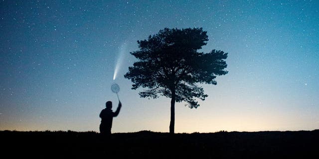 This stunning picture shows a man pretending to play badminton with Comet NEOWISE above the Quantock Hills in Somerset. (Credit: SWNS)