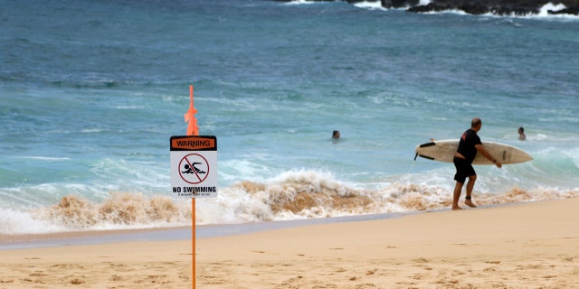 A surfer leaves the water in Honolulu, Saturday, July 25, 2020, as Hurricane Douglas approaches.