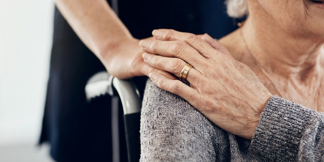 Cropped shot of caregiver comforting senior woman