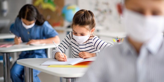 Small children with face masks back at school after COVID-19 quarantine and lockdown.