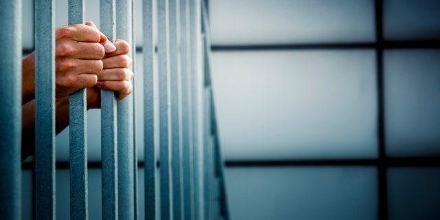 A prisoner behind jail cell bars.