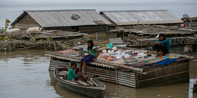 A flood affected family takes shelter on the roof of their submerged house along river Brahmaputra in Morigaon district, Assam, India, July 16.