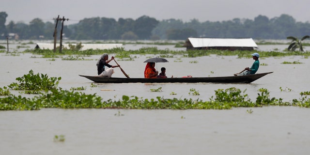 A family travels in a country boat over floodwaters in Gagolmari village, in Morigaon district of Assam, India, July 14.