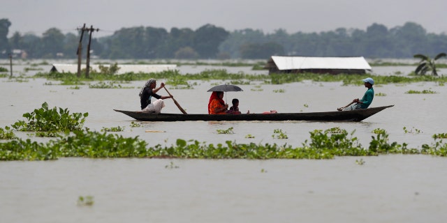 A family travels in a country boat over floodwaters in Gagolmari village, in Morigaon district of Assam, India, July 14.