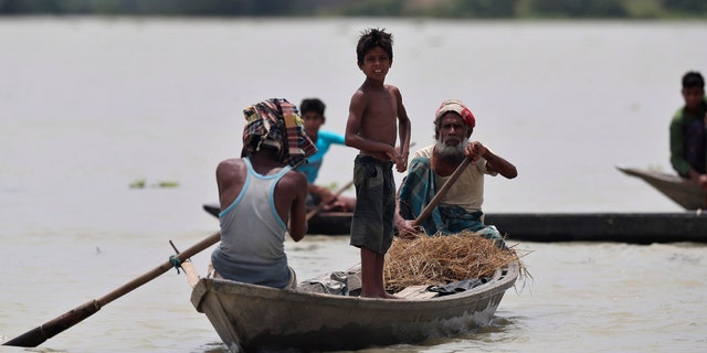 Indian flood affected people row country boats in Gagolmari village, Morigaon district, Assam, India, July 14.