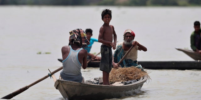 Indian flood affected people row country boats in Gagolmari village, Morigaon district, Assam, India, July 14.