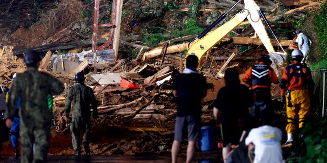 People watch a search operation at the site of a mudslide in Ashikita town, Kumamoto prefecture, southwestern Japan, Saturday, July 4, 2020.