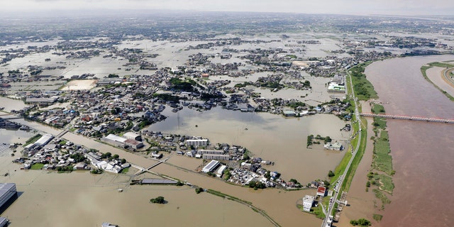 This aerial photo shows the flooded area near the swollen Chikugo River, right, in Kurume city, Fukuoka prefecture, southern Japan Wednesday, July 8, 2020.