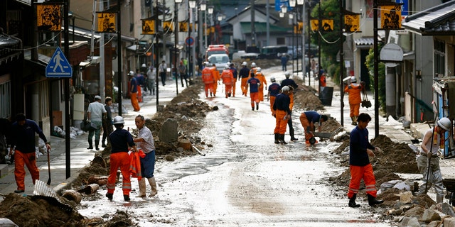 Residents and firefighters put away debris carried by the floodwater in Gero, Gifu prefecture, central Japan Wednesday, July 8, 2020.