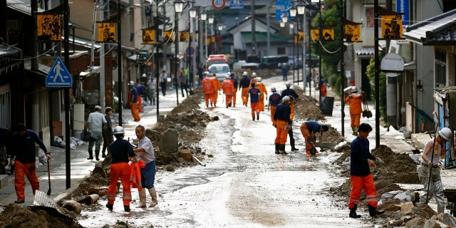 Residents and firefighters put away debris carried by the floodwater in Gero, Gifu prefecture, central Japan Wednesday, July 8, 2020.