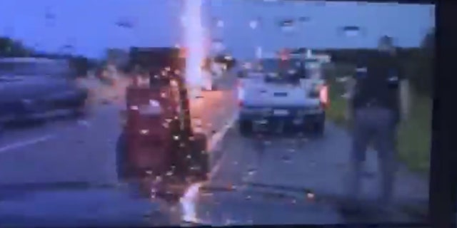 Lightning can be seen striking nearby as an Oklahoma Highway Patrol trooper assists a motorist.