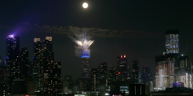 Macy's fireworks go off on the top of the Empire State Building as the full buck moon rises in the sky on July 4, 2020 as seen from Weehawken, New Jersey. (Photo by Gary Hershorn/FOX News)
