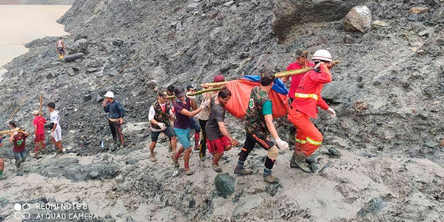 In this photo released from Myanmar Fire Service Department, rescuers carry a recovered body of a victim of a landslide from a jade mining area in Hpakant, Kachine state, northern Myanmar July 2.