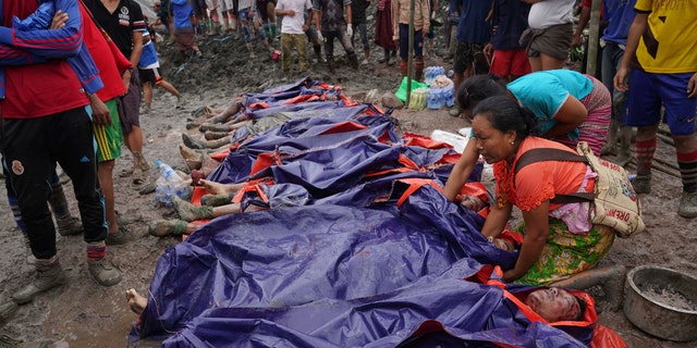 Women look at bodies shrouded in blue and red plastic sheets placed in a row on the ground July 2, in Hpakant, Kachin State, Myanmar.