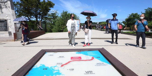People wearing face masks to help protect against the spread of the new coronavirus walk by a map of two Koreas showing North Korea's capital Pyongyang and South Korea's capital Seoul at the Imjingak Pavilion in Paju, near the border with North Korea, Sunday, July 26, 2020.
