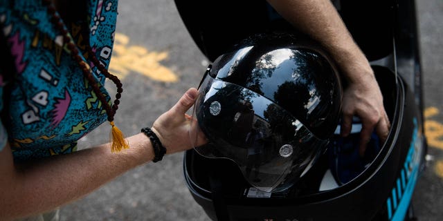 A commuter places a helmet back in the storage compartment of a Revel Transit Inc. electric ride share moped in the Williamsburg neighborhood of the Brooklyn borough of New York. (Photographer: Mark Kauzlarich/Bloomberg via Getty Images)