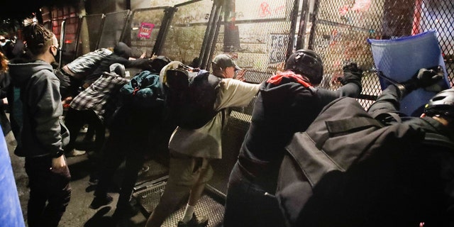 Demonstrators try to topple a steel fence during a Black Lives Matter protest at the Mark O. Hatfield United States Courthouse Saturday, July 25, 2020, in Portland, Ore. (AP Photo/Marcio Jose Sanchez)