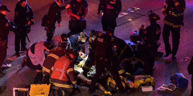 Emergency workers tend to an injured person on the ground after a driver sped through a protest-related closure on the Interstate 5 freeway in Seattle, authorities said early Saturday, July 4, 2020. (James Anderson via AP)