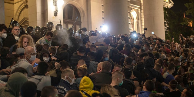 Police officers use pepper spray on demonstrators in front of the Serbian parliament in Belgrade, Serbia, on Tuesday. (AP)