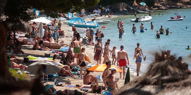 Sunbathers enjoy the beach in Pollença, in the Balearic Island of Mallorca, Spain, Tuesday, July 28, 2020. The U.K. government's recommendation against all but essential travel to the whole of Spain means that all travelers arriving in Britain from that country will have to undergo a 14-day quarantine. (AP Photo/Joan Mateu)