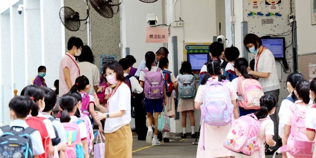 Students wearing face masks wait in line to have body temperatures checked at the entrance of a school on June 15, 2020, in Hong Kong, China. (Hong Fan/China News Service via Getty Images)