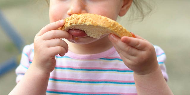 A very adorable, and concerned, looking tot was captured on camera by his mother hoarding a loaf of sliced sandwich bread and taking small nibbles out of the corners.