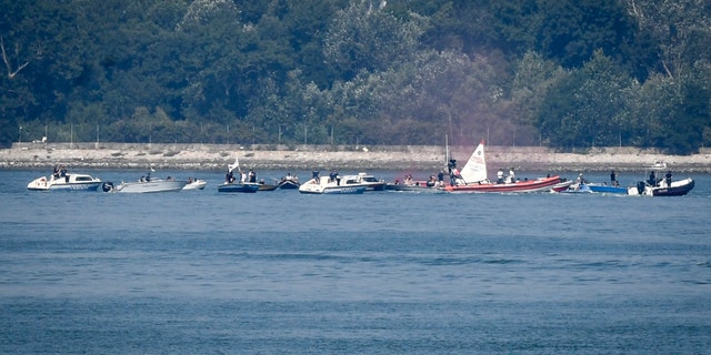 Environmentalists in small boats near the test site of a trial run of the anti-flood system wave protest banners as police speed boats head their way. (AP/LaPresse)