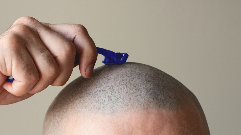Man shaving his head with a razor