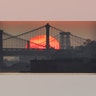The sun rises behind the Brooklyn Bridge, Manhattan Bridge and Williamsburg Bridge in New York City, July 18, 2020.