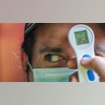 A worker measures the temperature of a man before allowing him to enter the La Vega market in Santiago, Chile, July 19, 2020.