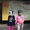 Girls wearing face shields as a preventive measure against the coronavirus wait for their parents to enter the zoo in Quito, Ecuador, July 8, 2020.